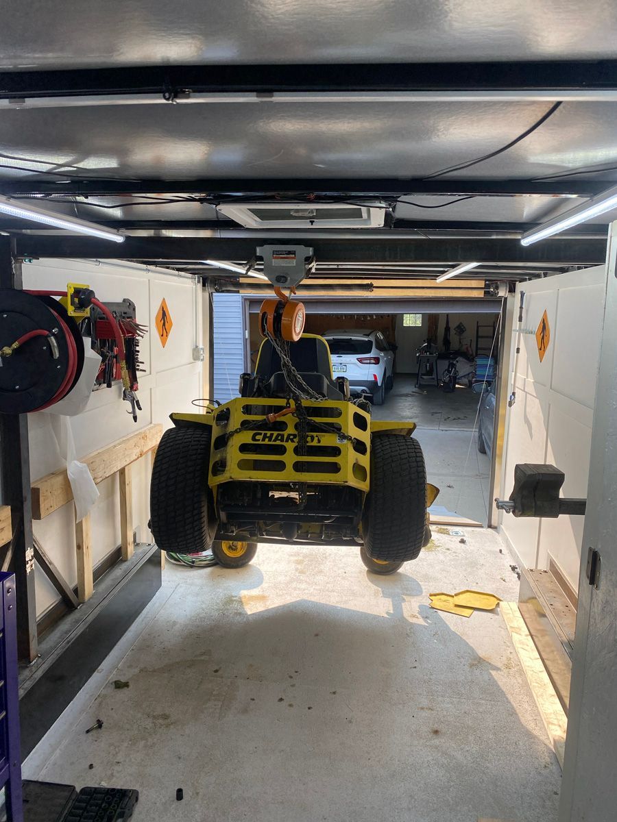 A man is driving a yellow atv in a garage.
