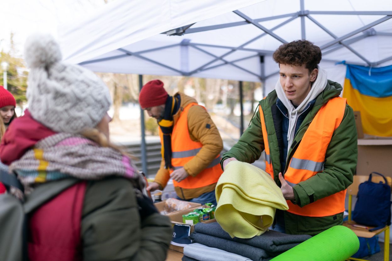 A man doing community outreach offers an unhoused person a blanket - cleanup usa, tx