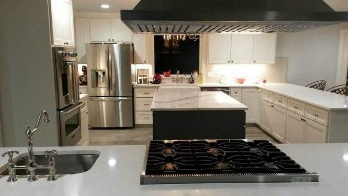 A kitchen with a stove top oven , refrigerator , sink and stainless steel appliances.