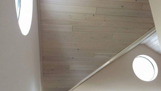 A staircase with a wooden floor and two round windows.