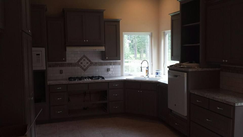 A kitchen with brown cabinets , a stove , a sink , and a window.