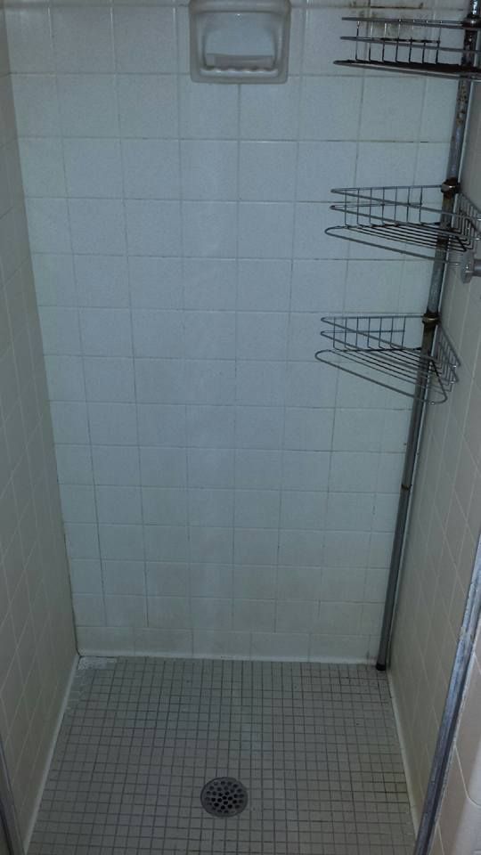 A shower stall with a tiled floor and a drain.