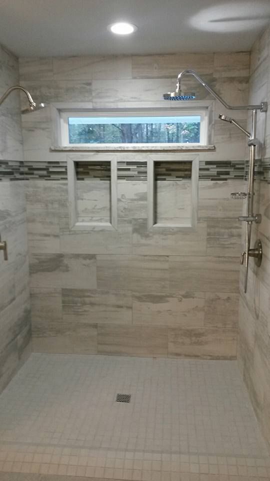 A walk in shower with two shower heads and a window.