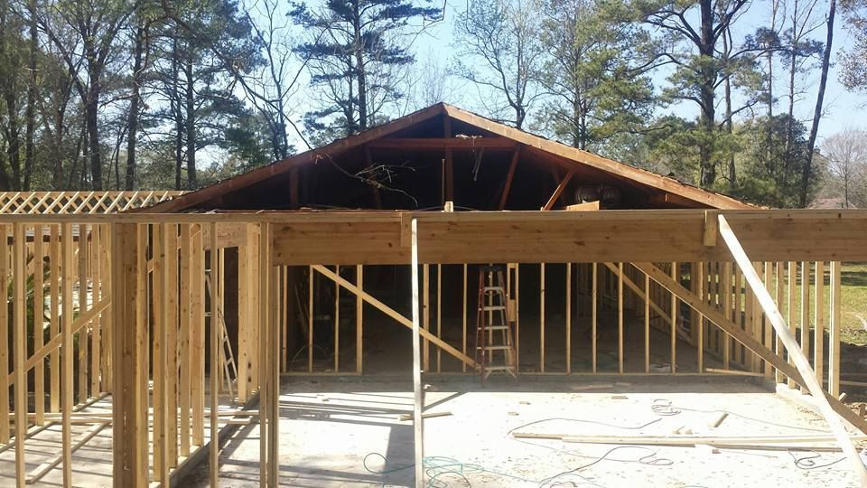 A house is being built with a wooden frame surrounded by trees.