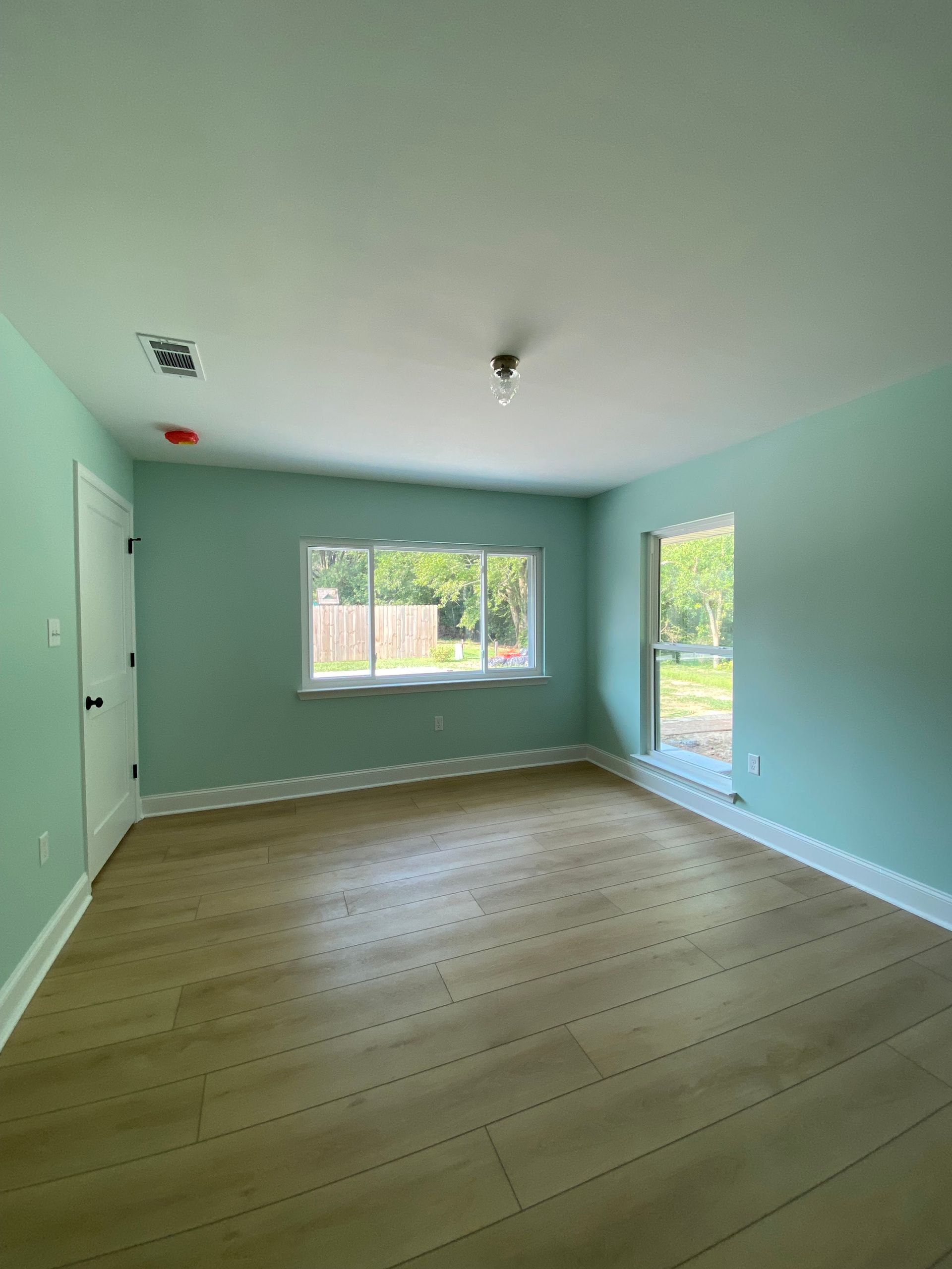 An empty room with wooden floors and green walls.