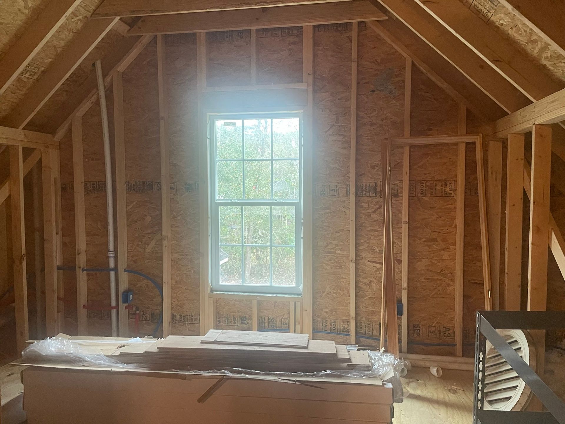 There is a window in the attic of a house under construction.