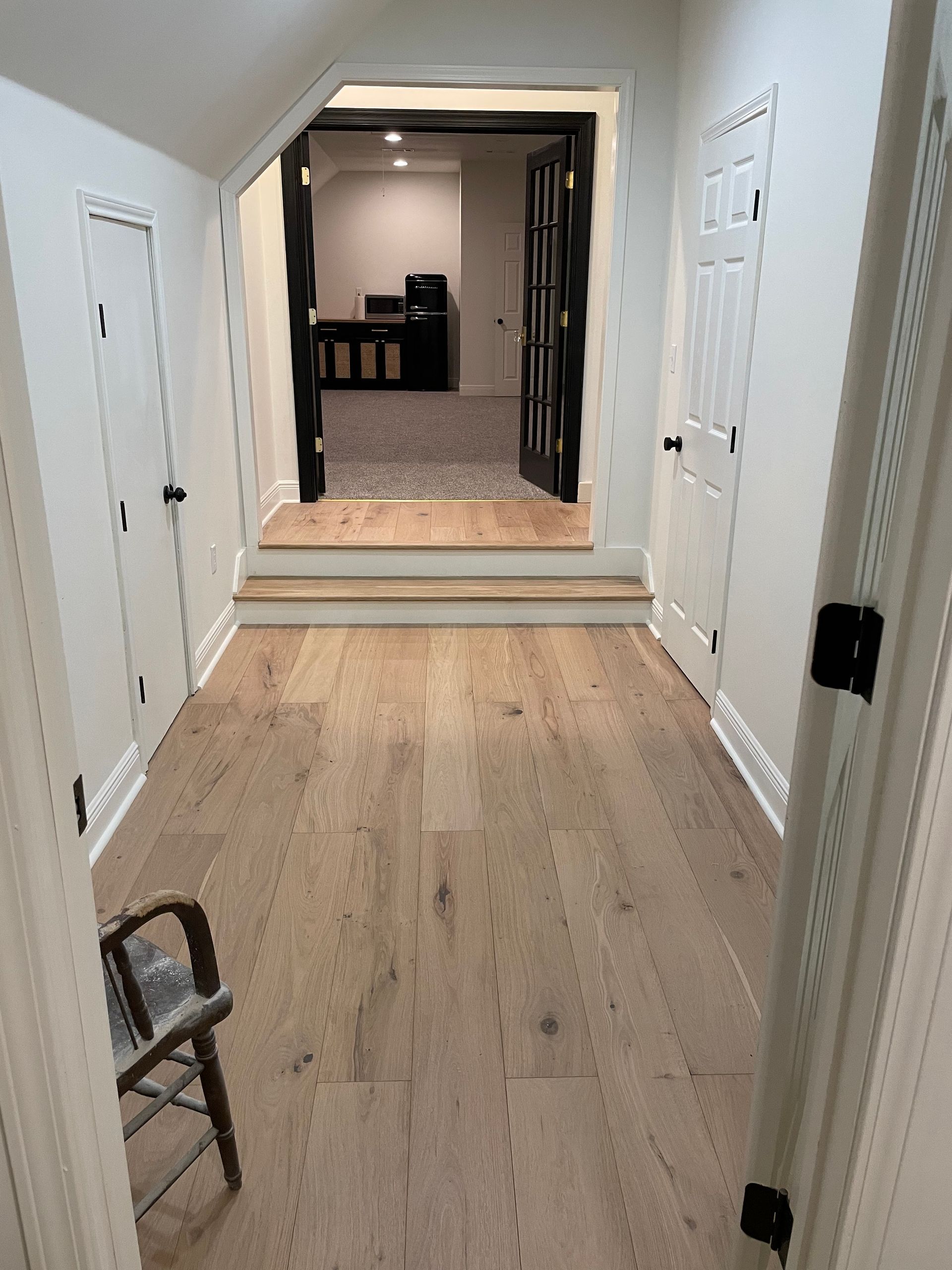 A hallway with hardwood floors and a chair in the middle of it.