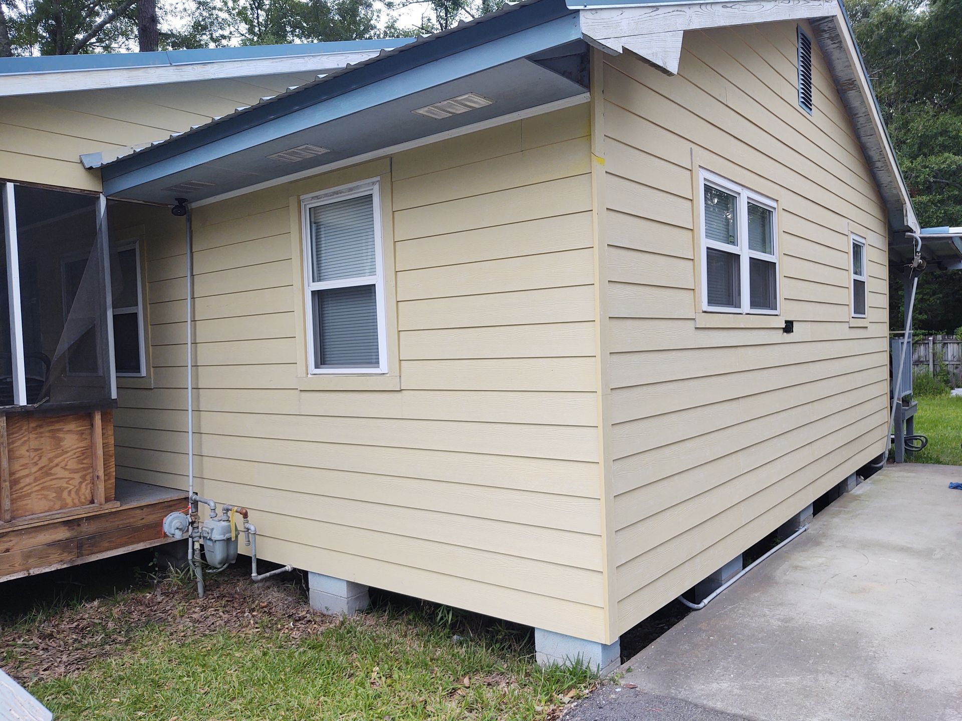 A small house with a screened in porch and a blue roof