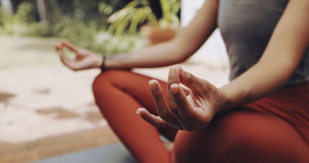 A woman is sitting in a lotus position on a yoga mat.