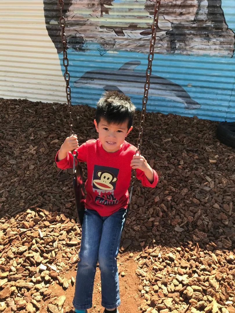 Boy Sitting on a Swing — Sacramento, CA — Tot Town Child Development Center, Inc.