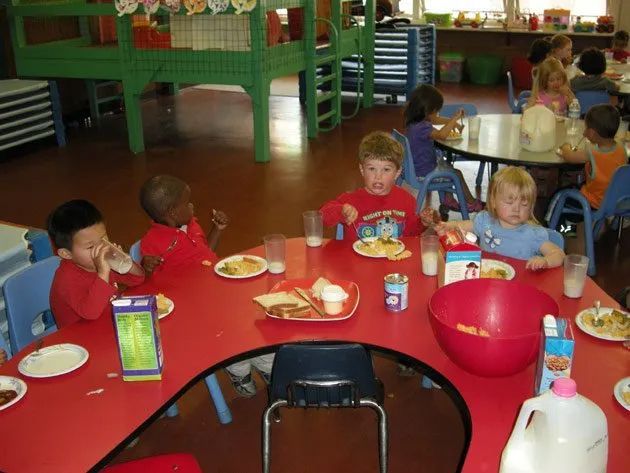 Children Eating on a Red Table — Sacramento, CA — Tot Town Child Development Center, Inc.