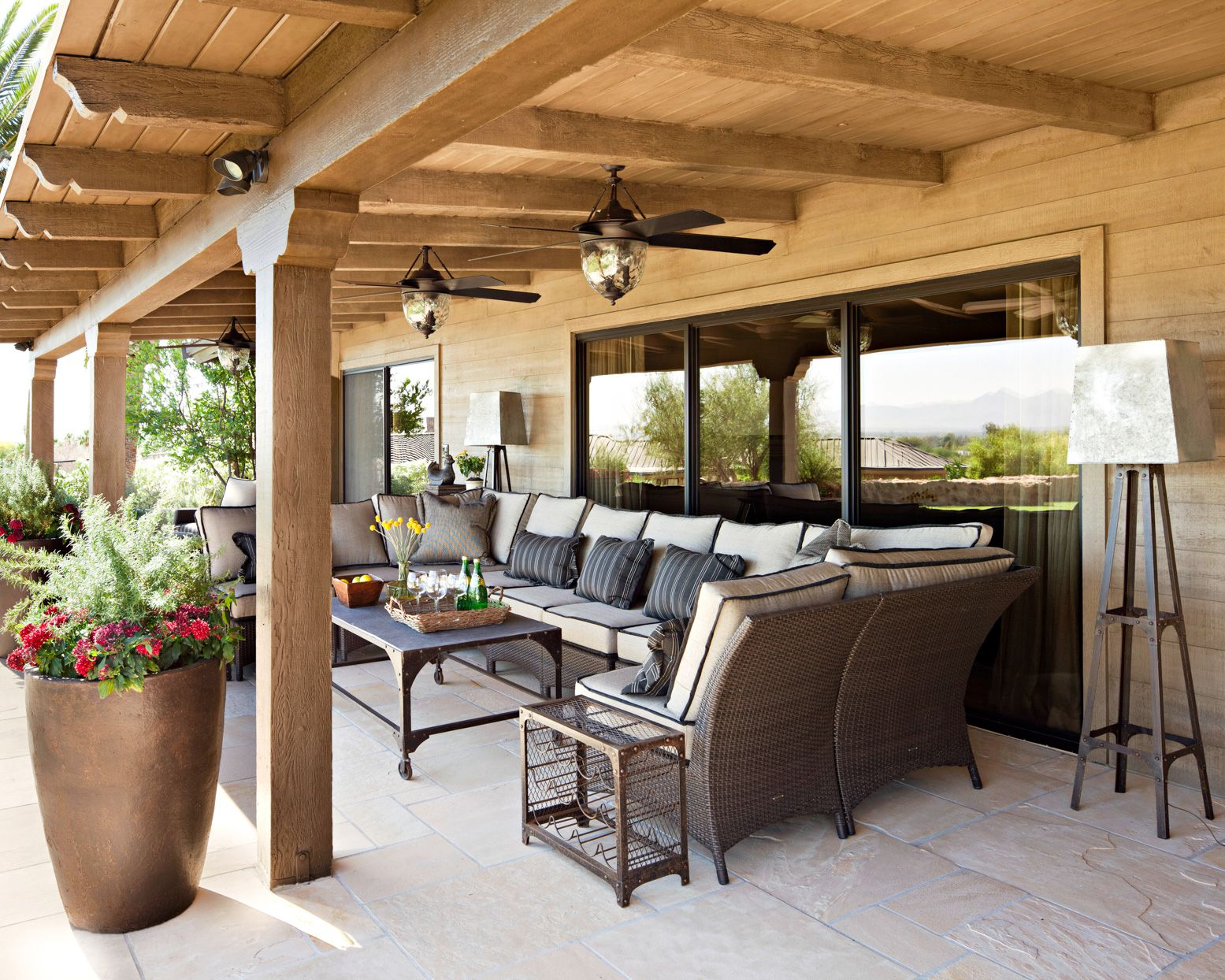 Patio with outdoor furniture under a wooden pergola, tan walls, and a view of the landscape.