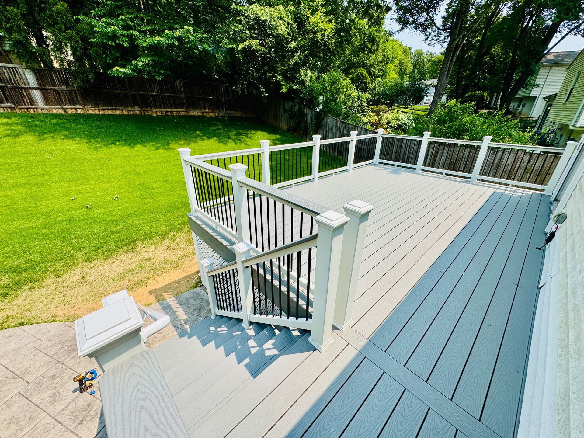 Gray composite deck with white and black railings, overlooking a green lawn.