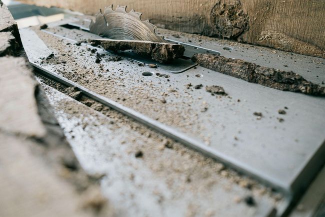 Close-up of a saw blade cutting through concrete, covered in dust and debris.