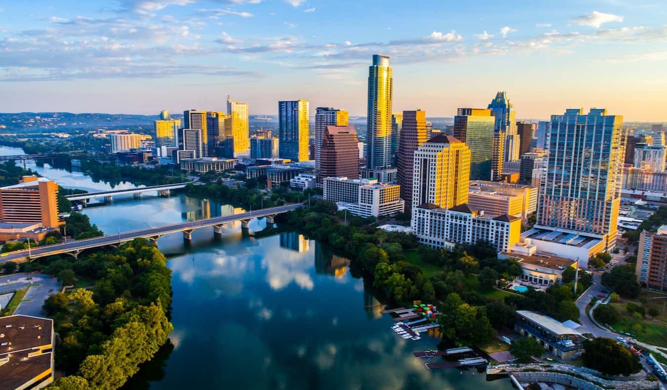 An aerial view of a city skyline with a river in the foreground.