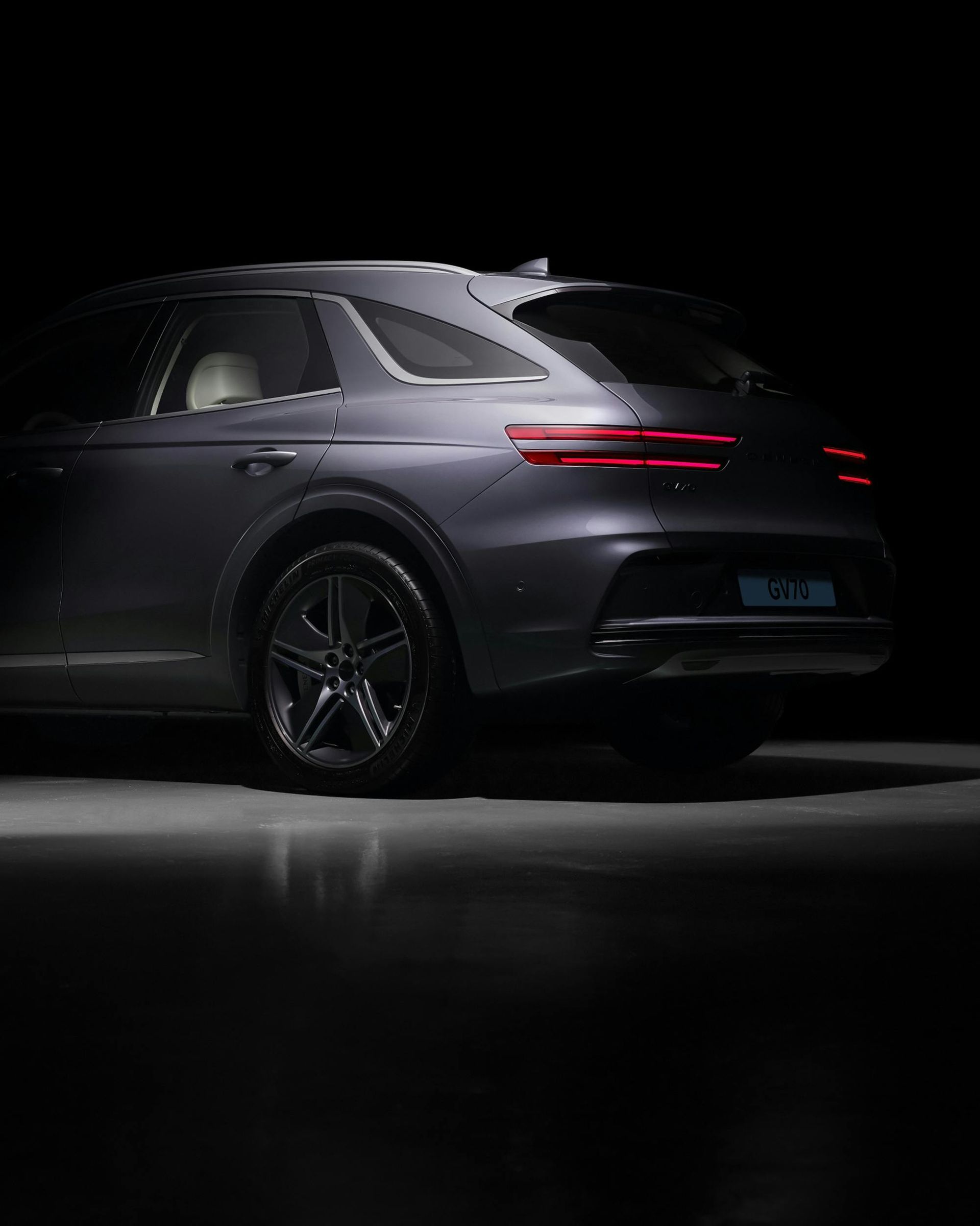 A gray suv with safety lights is parked in a dark room.