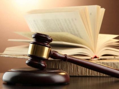 Gavel on wooden block in front of open law books.