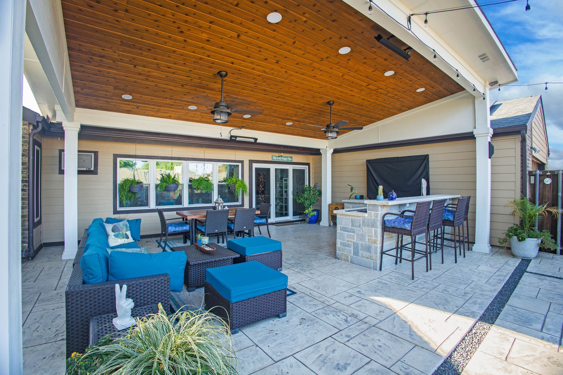 A large patio with a wooden ceiling and lots of furniture