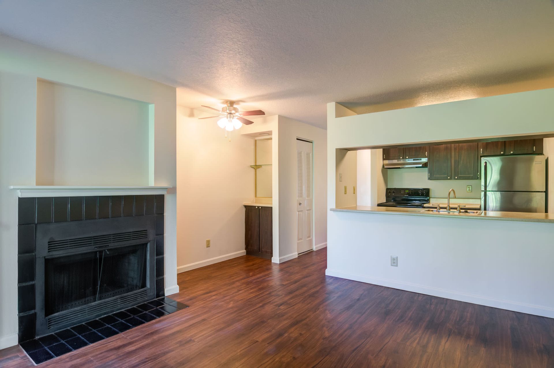 Open-concept living area with a dark fireplace on the left and a pass-through kitchen on the right at Ansley Murrayhill in Tigard, OR.