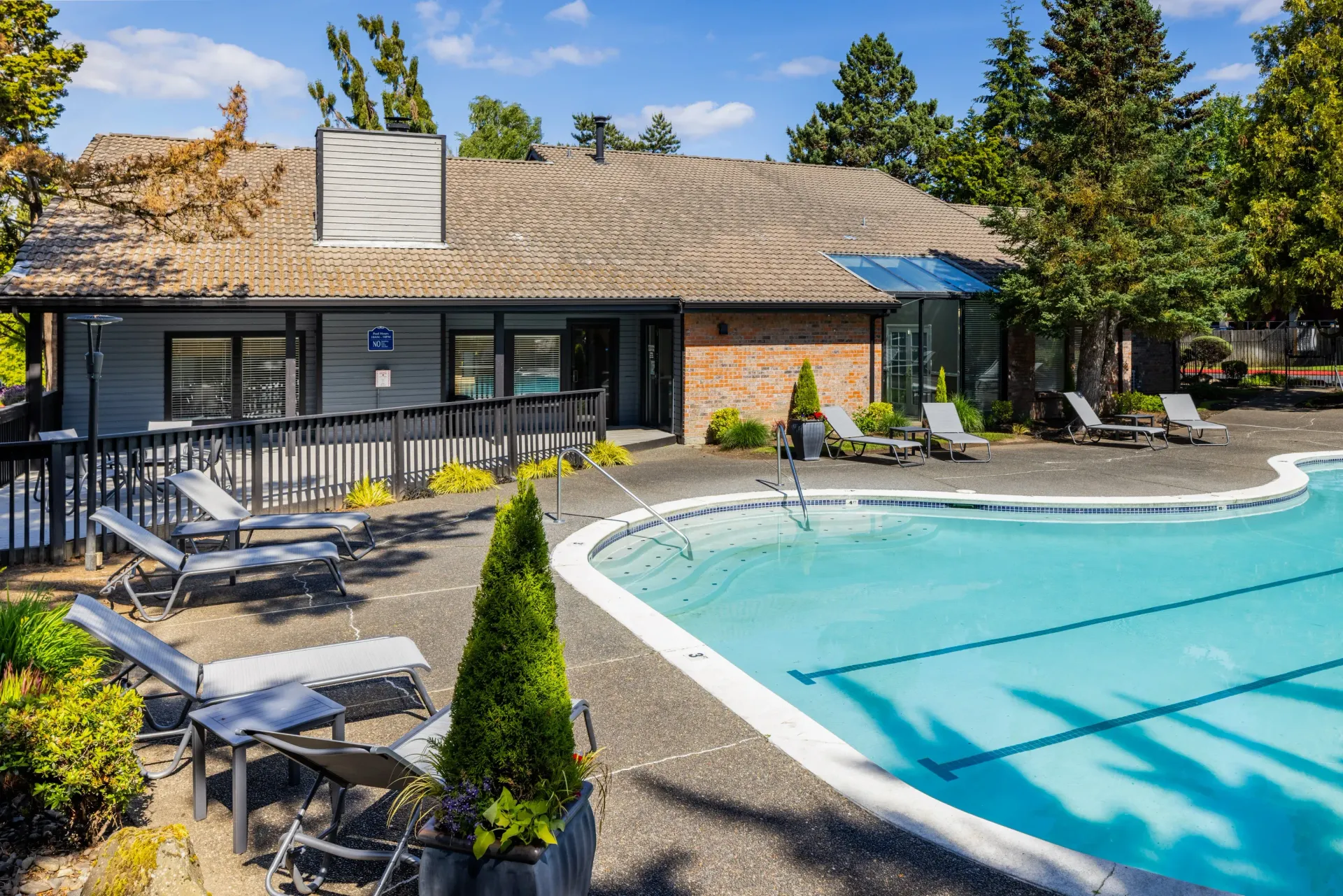 Outdoor apartment community pool with lounge chairs around the deck at Ansley Murrayhill in Tigard, OR.