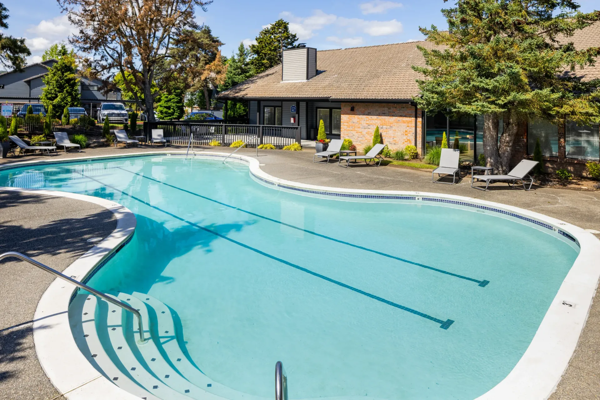 Outdoor pool at an apartment community with lounge chairs and surrounding landscaping at Ansley Murrayhill in Tigard, OR.