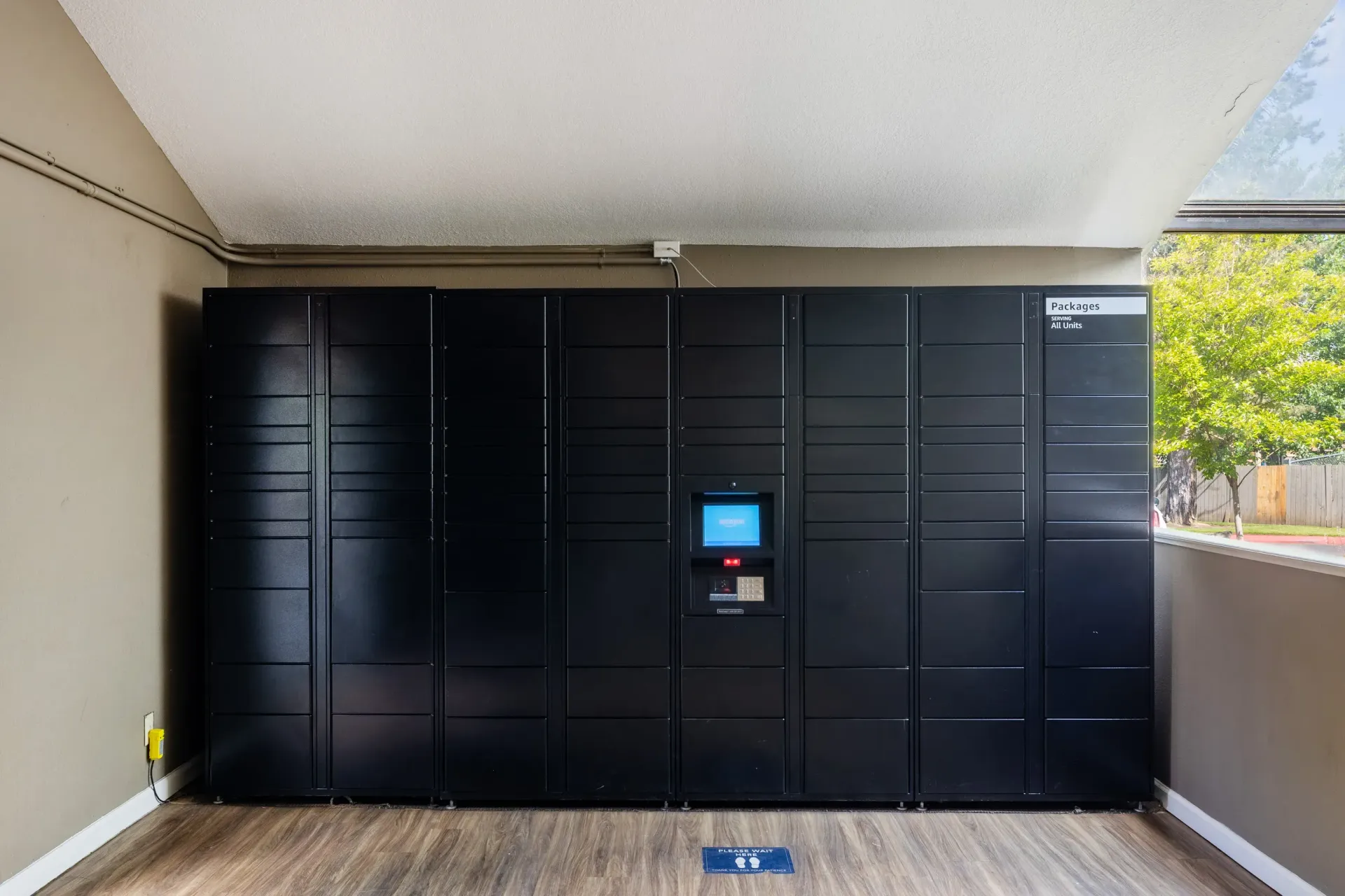 Row of black parcel lockers with a central automated locker and keypad in a hallway at Ansley Murrayhill in Tigard, OR.