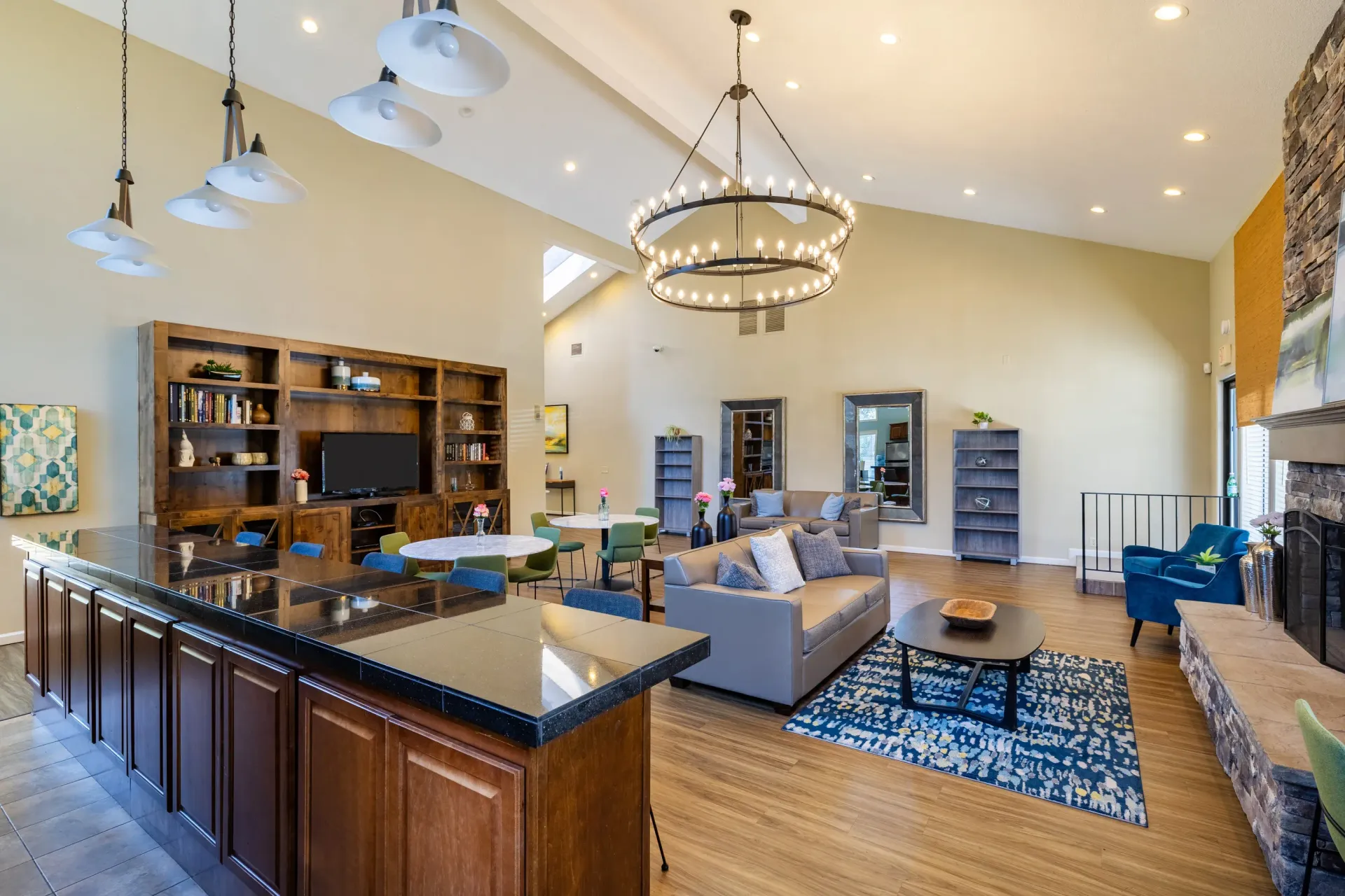 Spacious residential lounge with a large island, seating areas, fireplace, and a circular chandelier at Ansley Murrayhill in Tigard, OR.