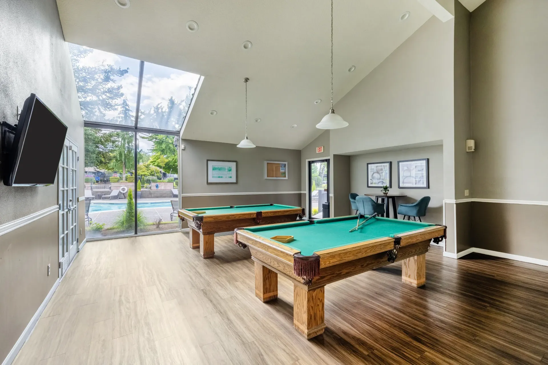 Interior community recreation room with two pool tables and a large window wall overlooking the outdoor pool at Ansley Murrayhill in Tigard, OR.