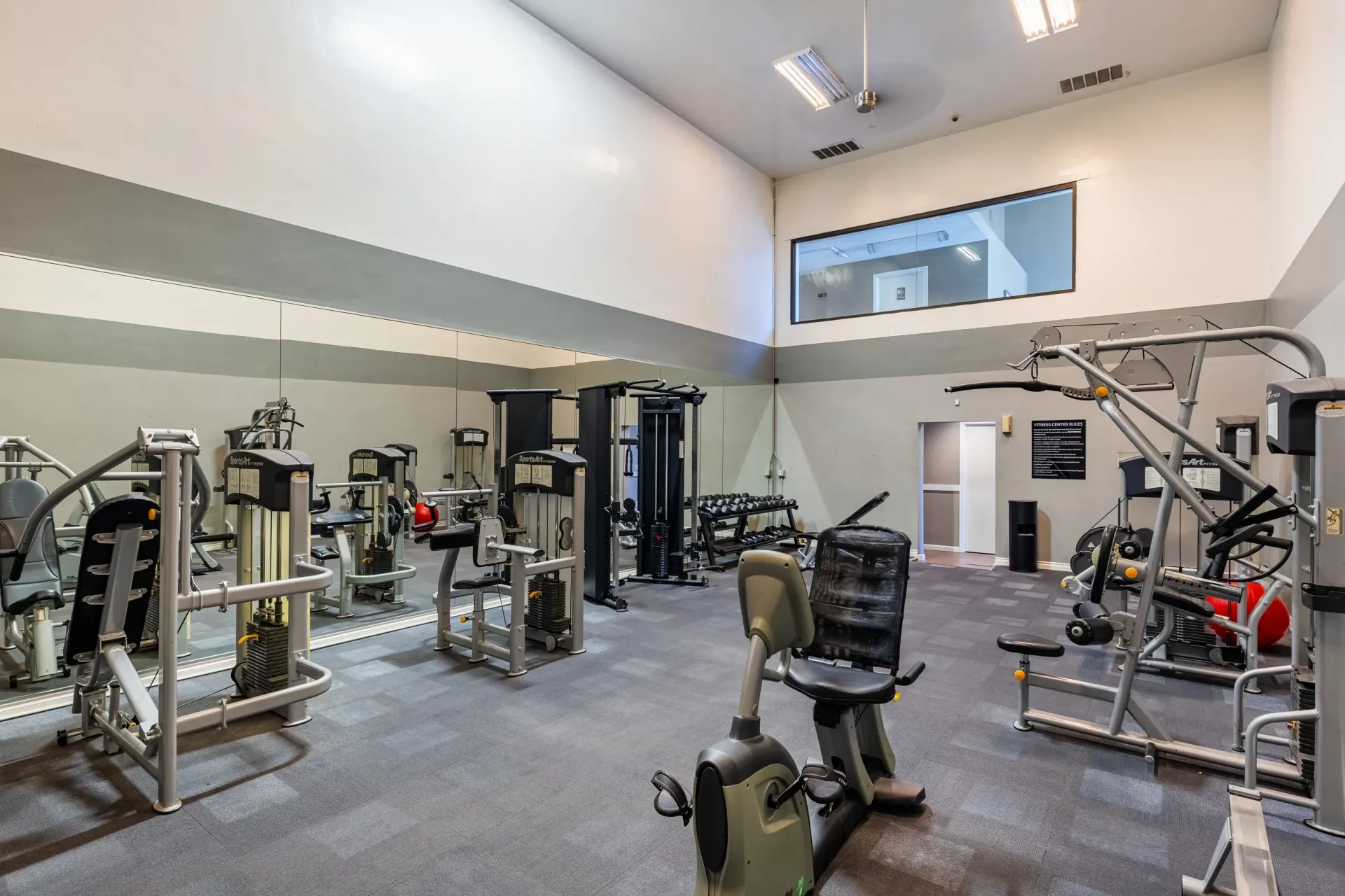 Interior of a communal fitness center with cardio machines, weight machines, and free weights at Ansley Murrayhill in Tigard, OR.