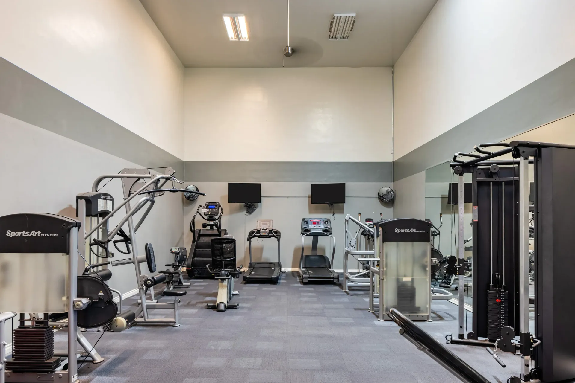 Fitness center with cardio machines and weight equipment in a neutral-toned workout room at Ansley Murrayhill in Tigard, OR.