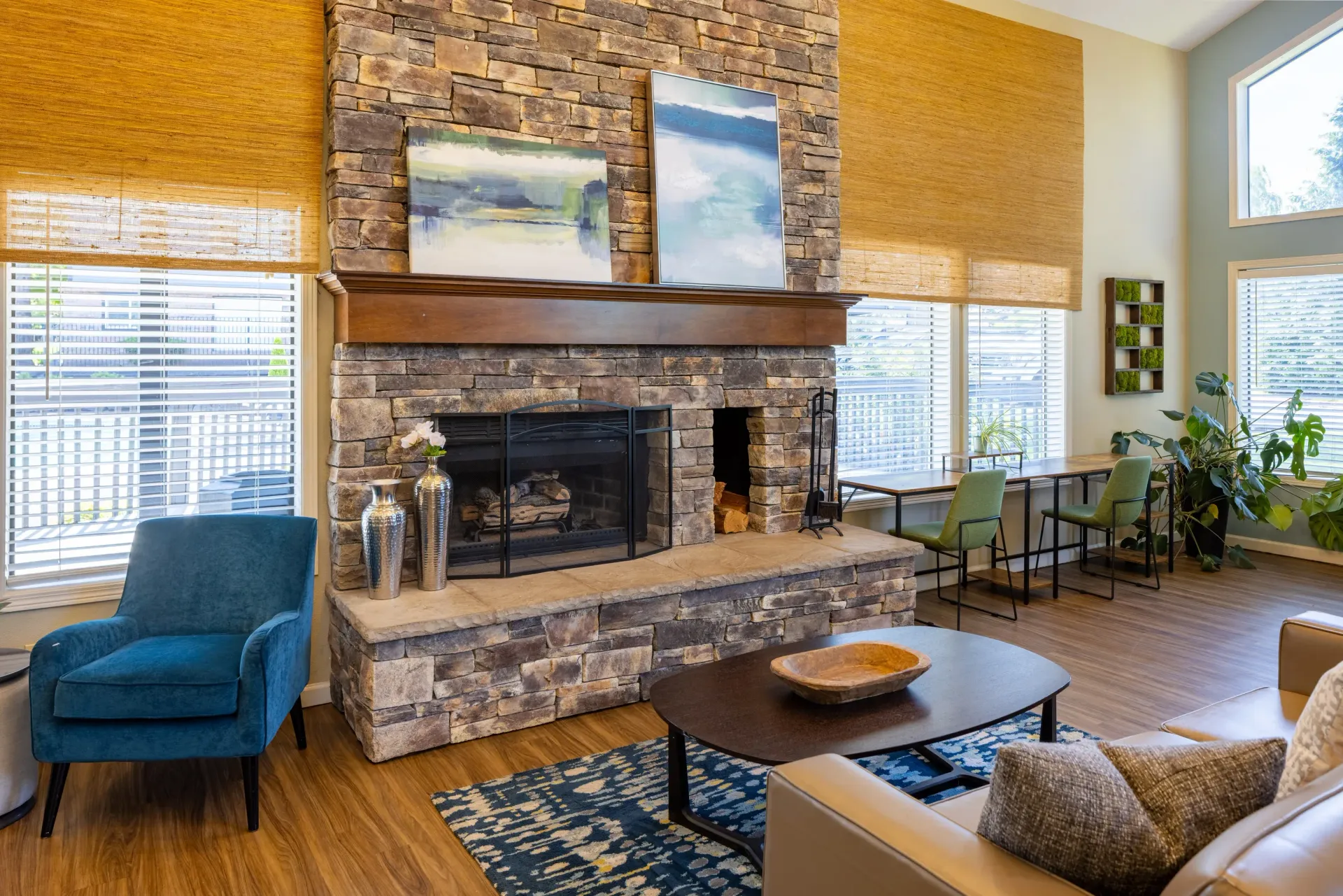 Bright communal living area with a stone fireplace, modern seating, and large windows at Ansley Murrayhill in Tigard, OR.