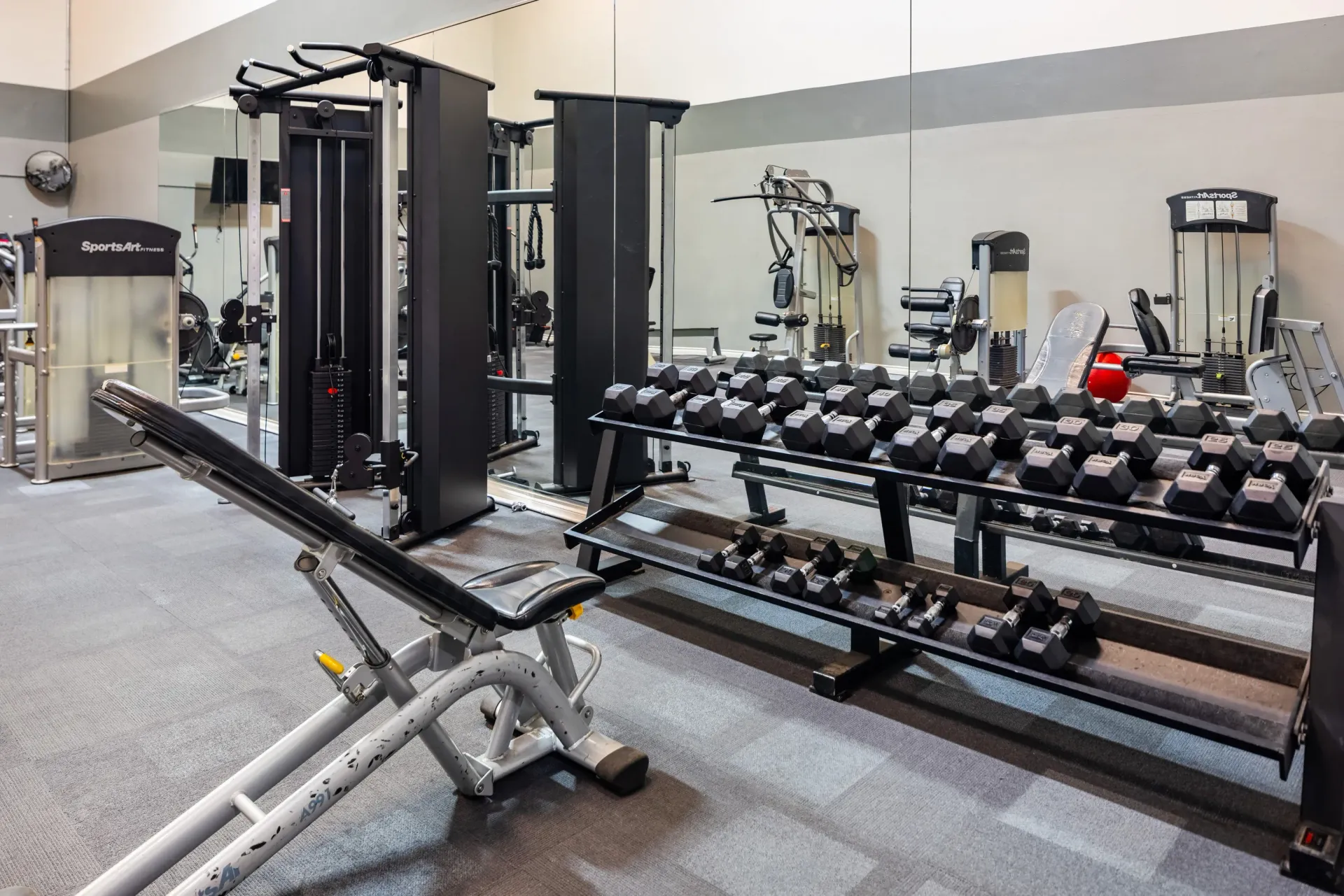 Apartment community gym with free weights and weight machines at Ansley Murrayhill in Tigard, OR.
