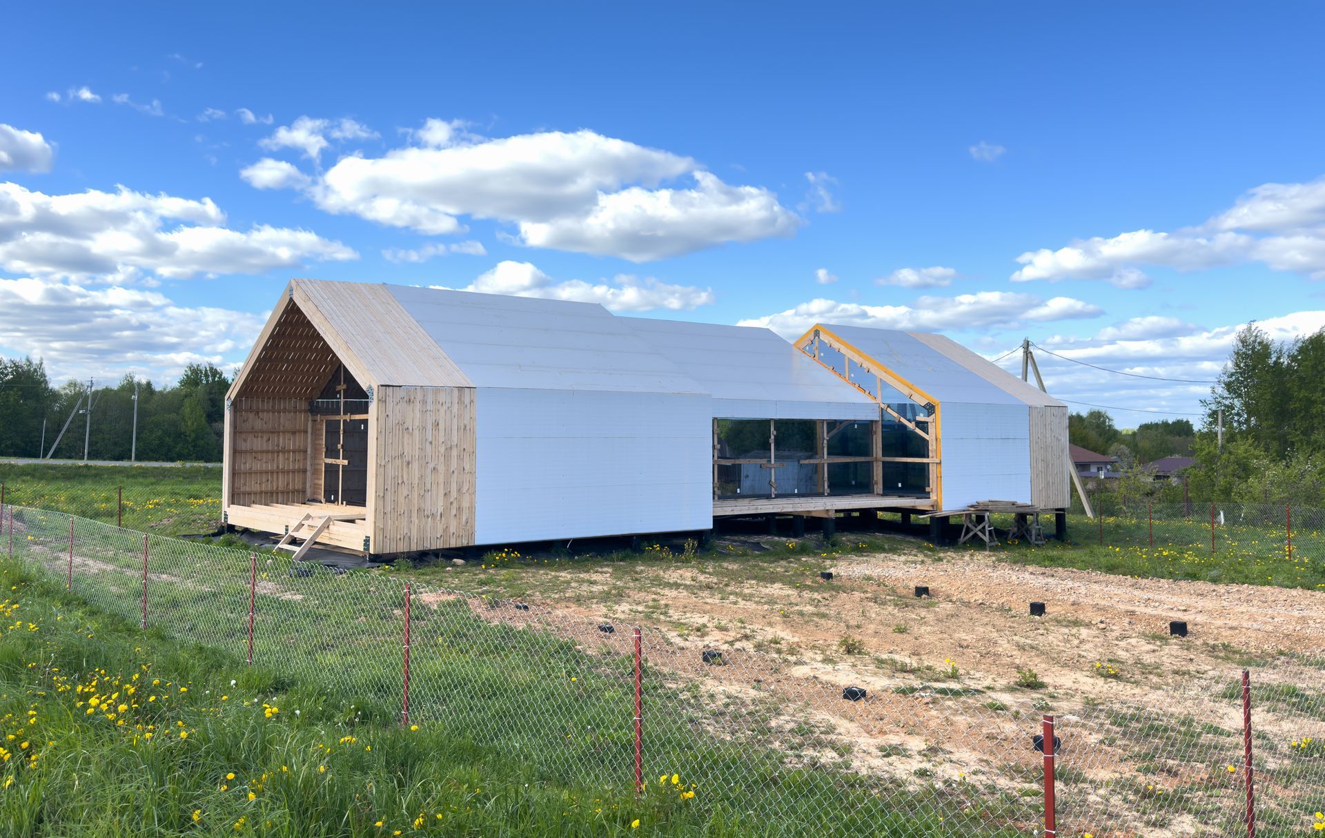 Construction of a modern house; wooden frame and white siding; cloudy sky.