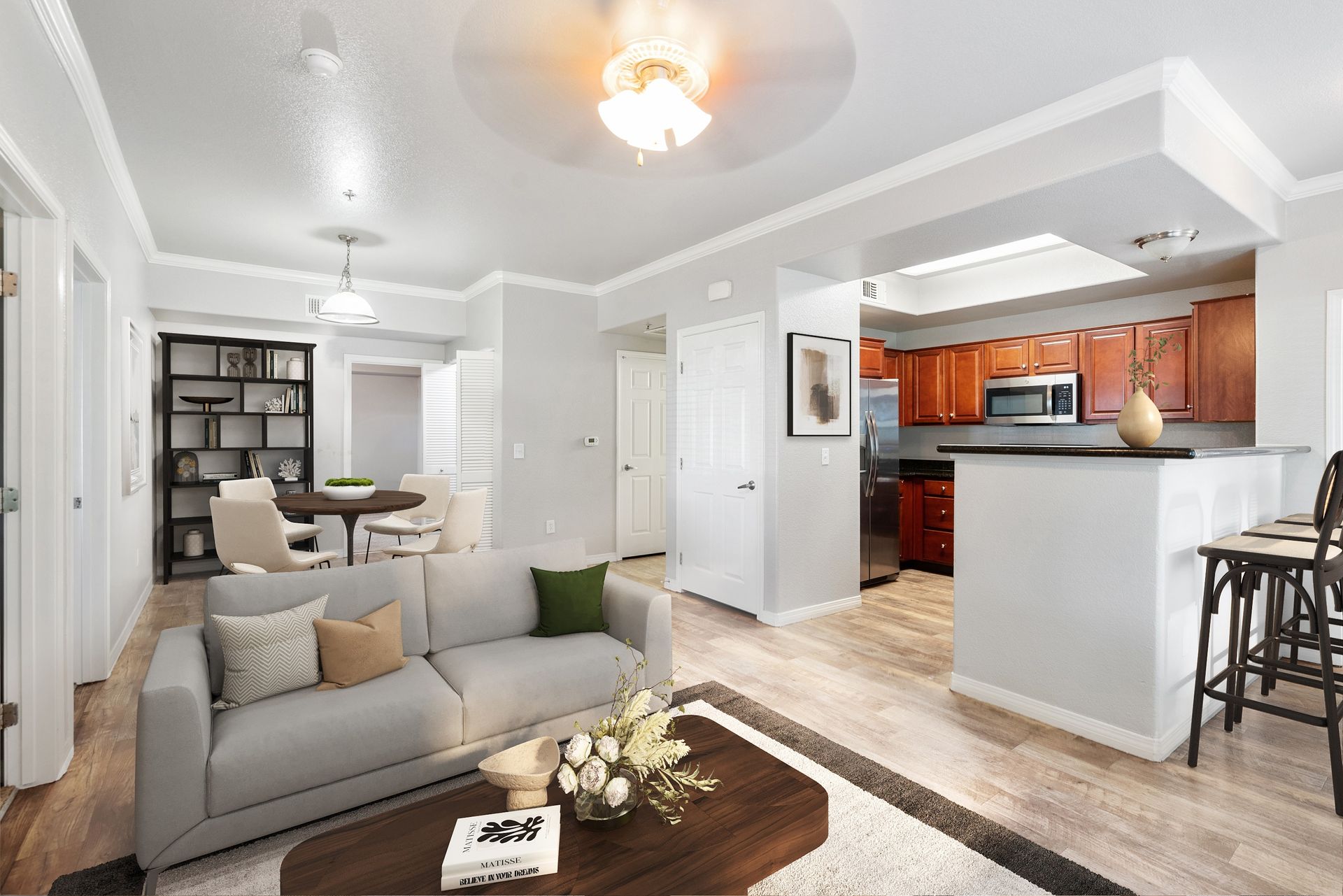 Open-concept living area with a light gray sofa, dining table, and a kitchen with a bar counter.