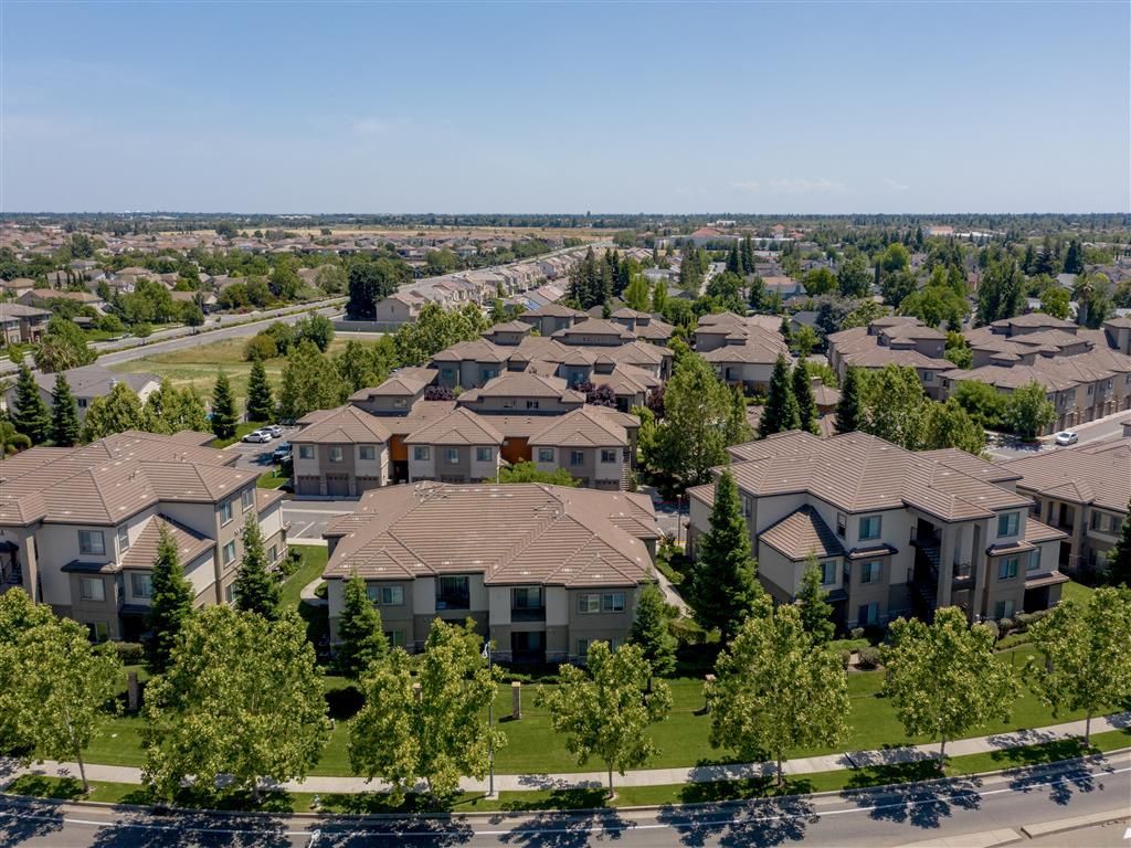Aerial view of a beige apartment community with clustered buildings, green lawns, and tree-lined streets.