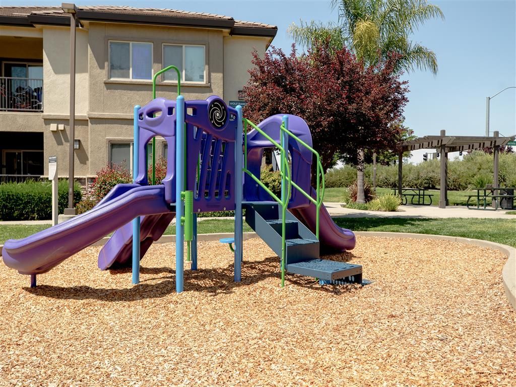 Outdoor playground with purple slides and green rails in a residential courtyard.