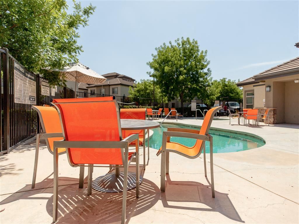 Outdoor pool area with bright orange chairs around a curved pool.