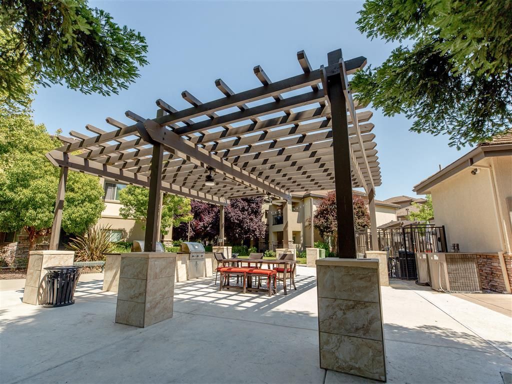 Outdoor community space with a large pergola, seating, and grills.