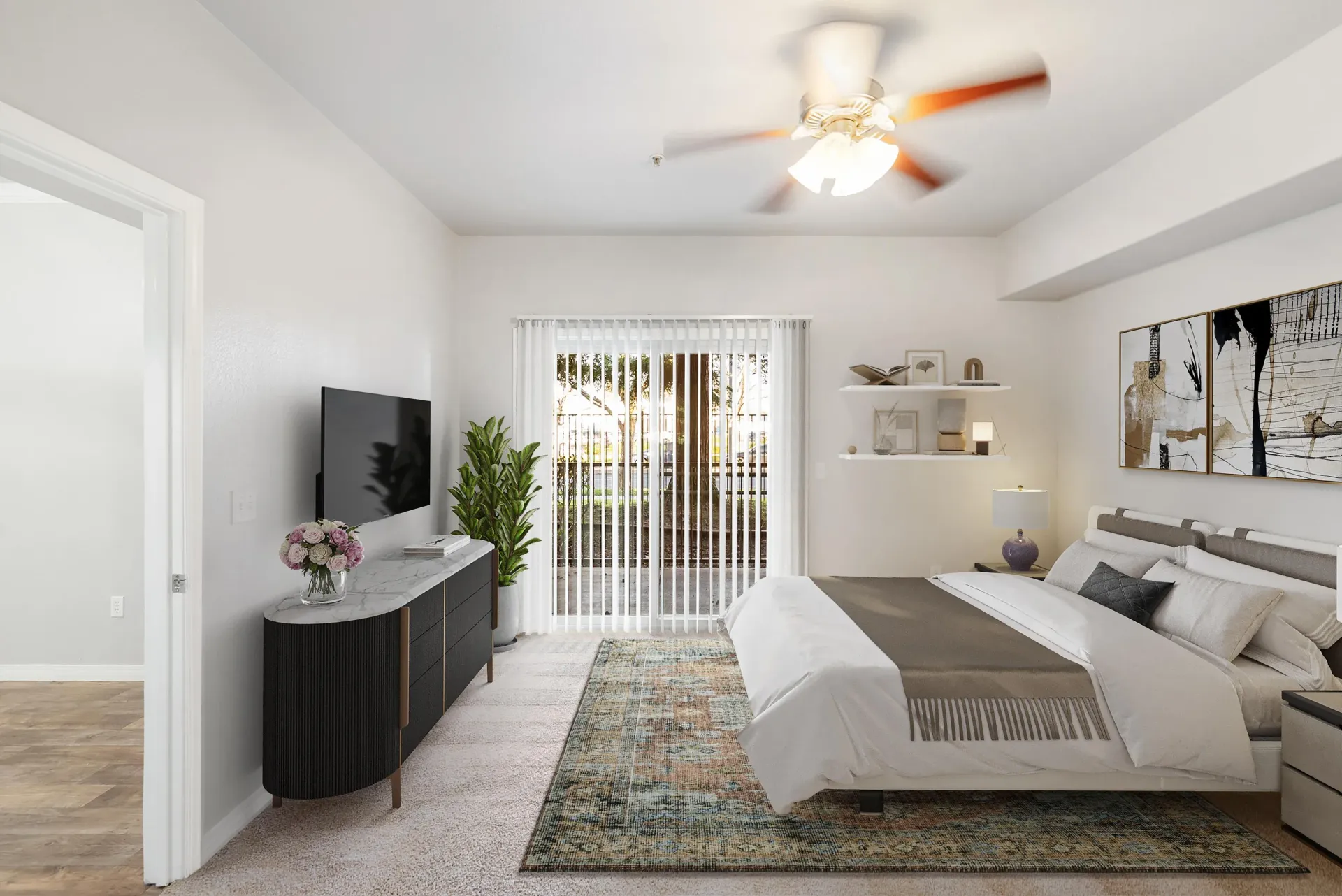 Bedroom in a modern apartment with a bed, dresser, wall TV, and sliding glass door to a patio.