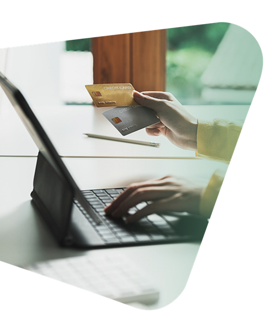 A person holding two credit cards while typing on a laptop computer.