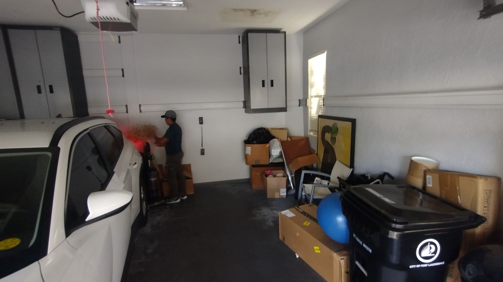 A man is standing in a garage next to a white car