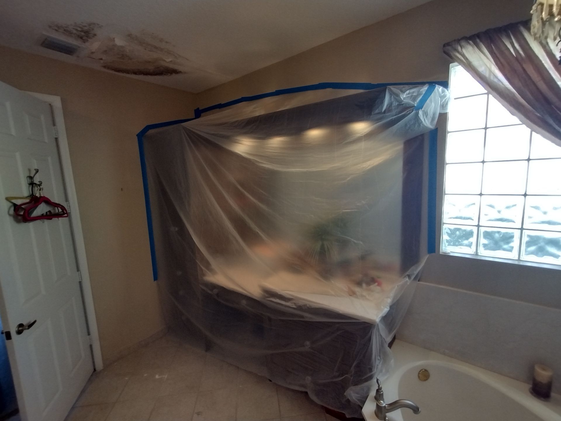 A bathroom with a vanity and tub covered in plastic