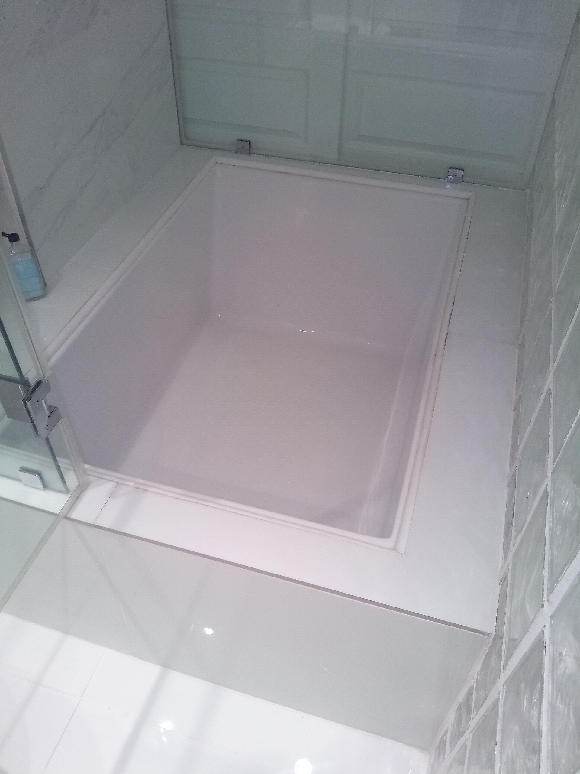 A white bathtub in a bathroom with a glass door.