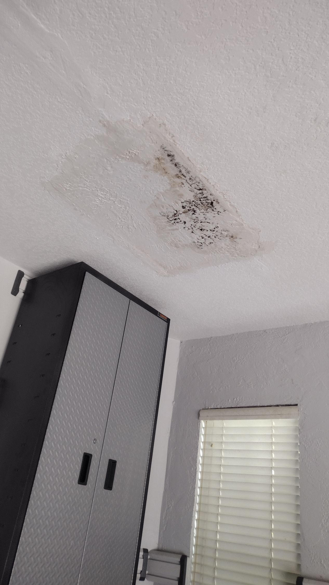 A room with a ceiling that has a hole in it and a window.