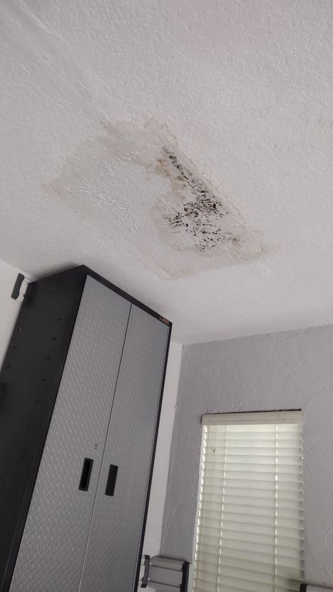 A room with a ceiling that has a hole in it and a window.