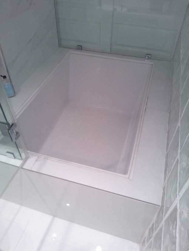 A white bathtub in a bathroom with a glass door.