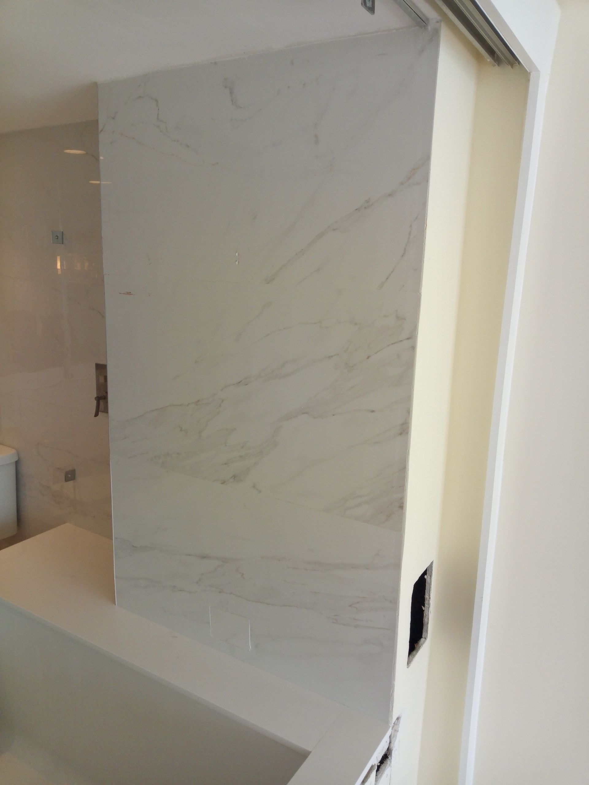 A bathroom with a bathtub and a marble wall.
