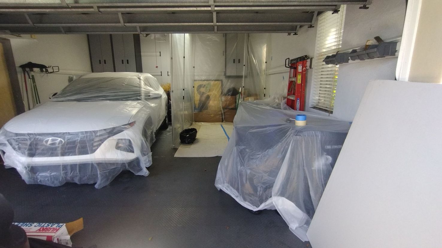 A car is wrapped in plastic in a garage.