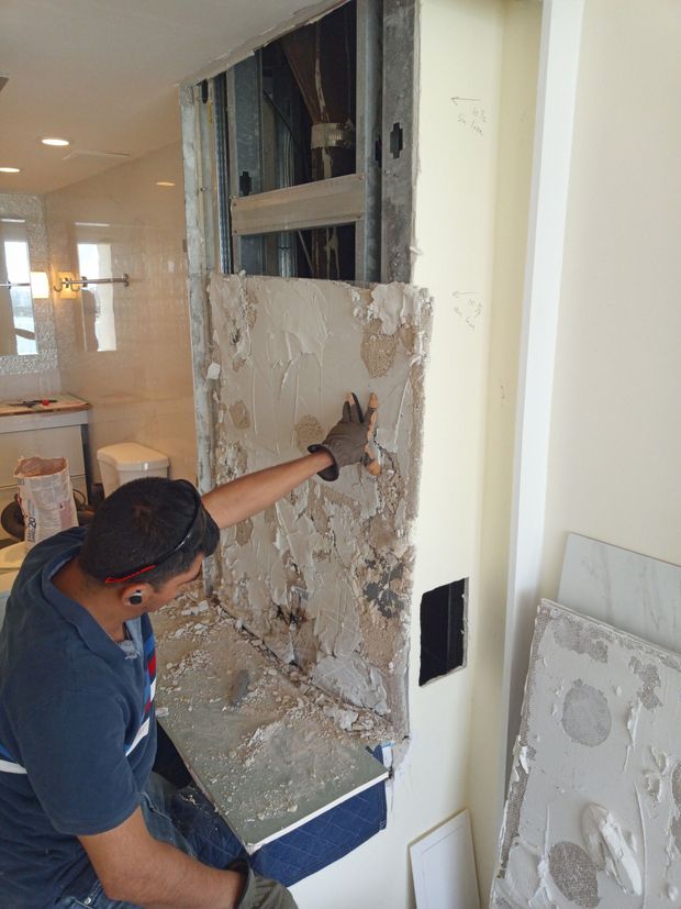 A man is working on a wall in a bathroom