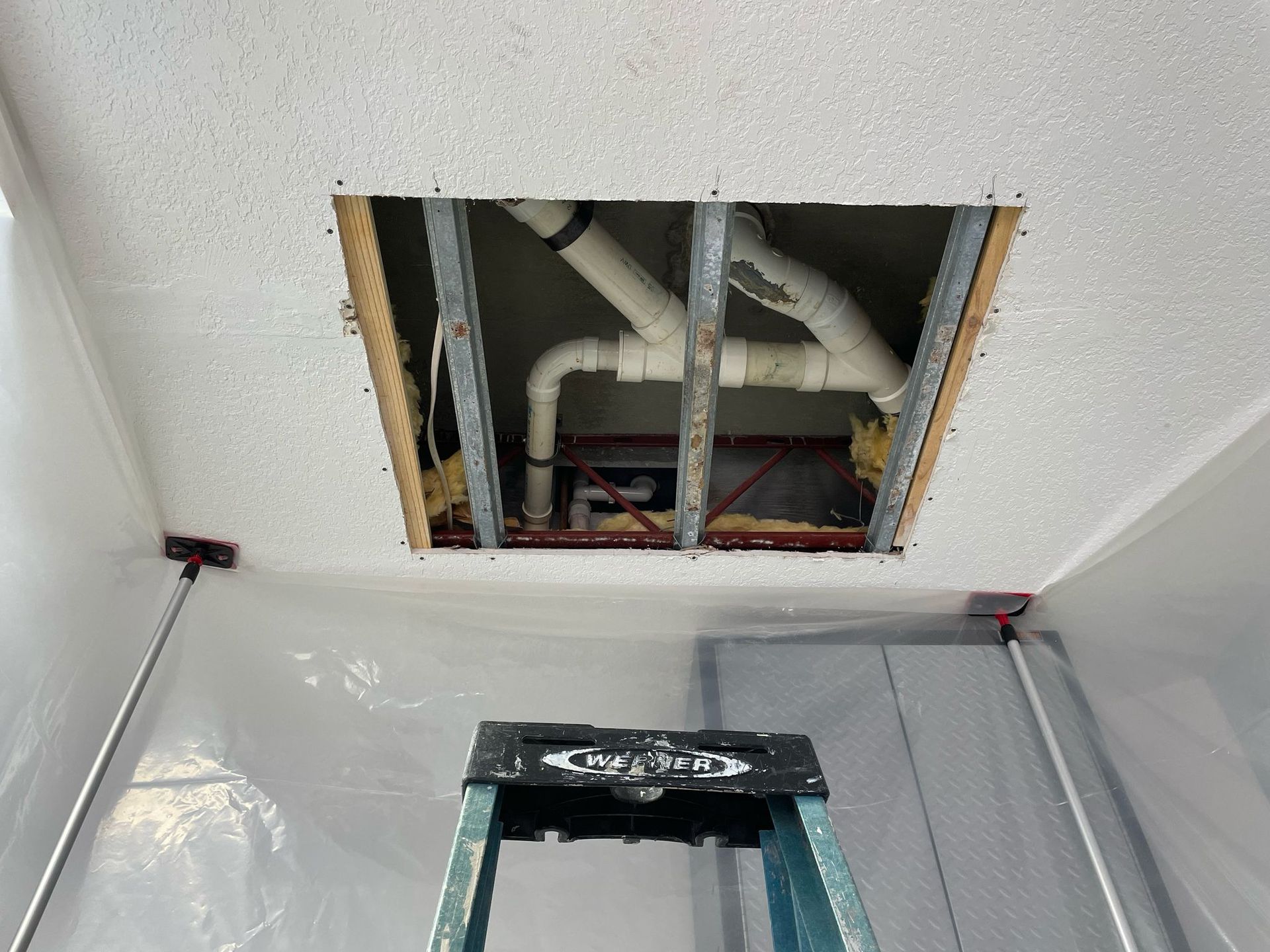 A ladder is sitting in a room with a hole in the ceiling.